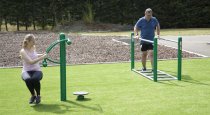 Två personer tränar på Twister och parallella utegymredskap i parkmiljö