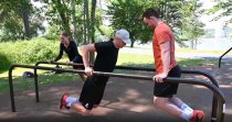 Tre personer tränar dips och kroppsviktsträning på Parallellbars i utegym